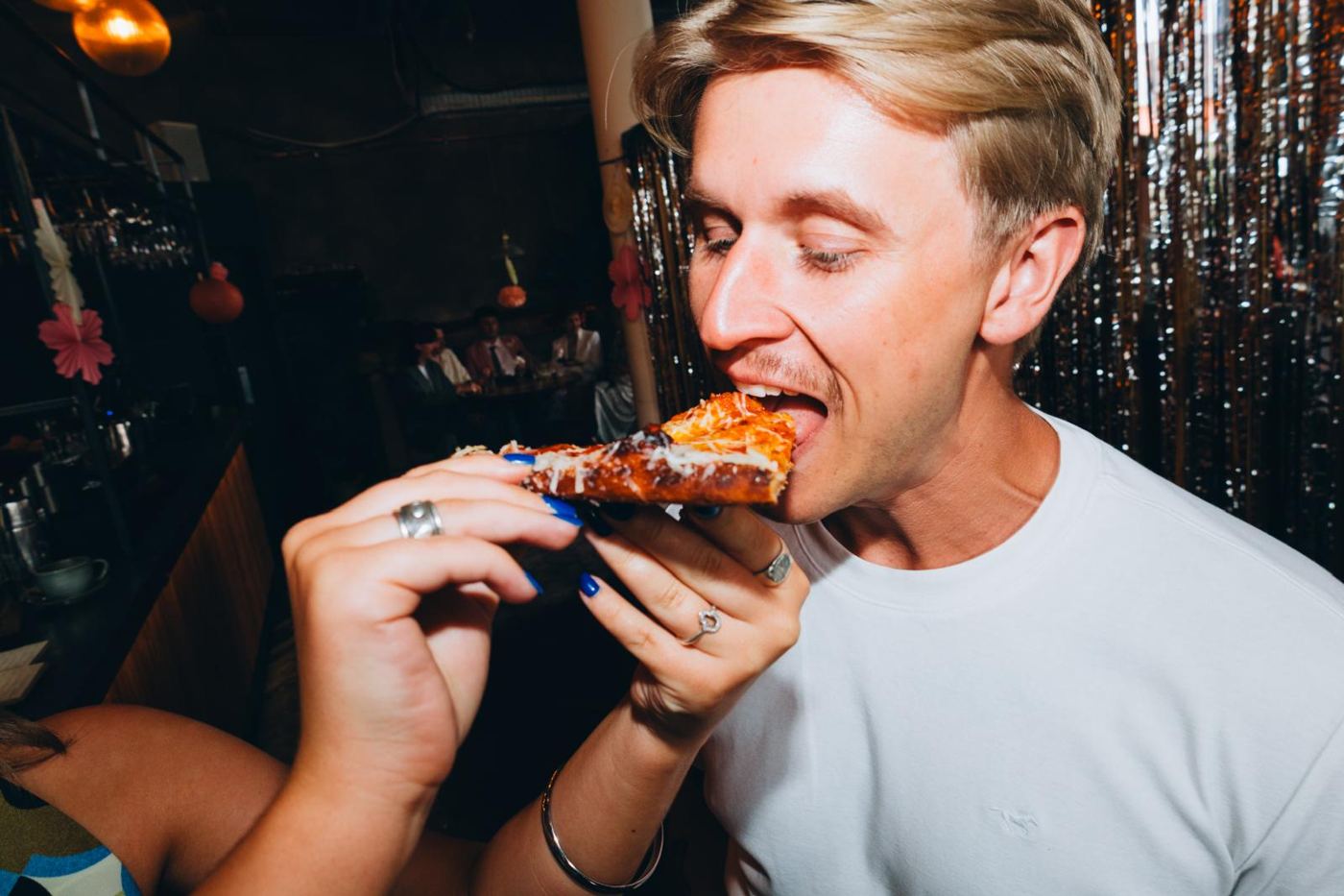 Someone being fed a slice in front of a tinsel curtain