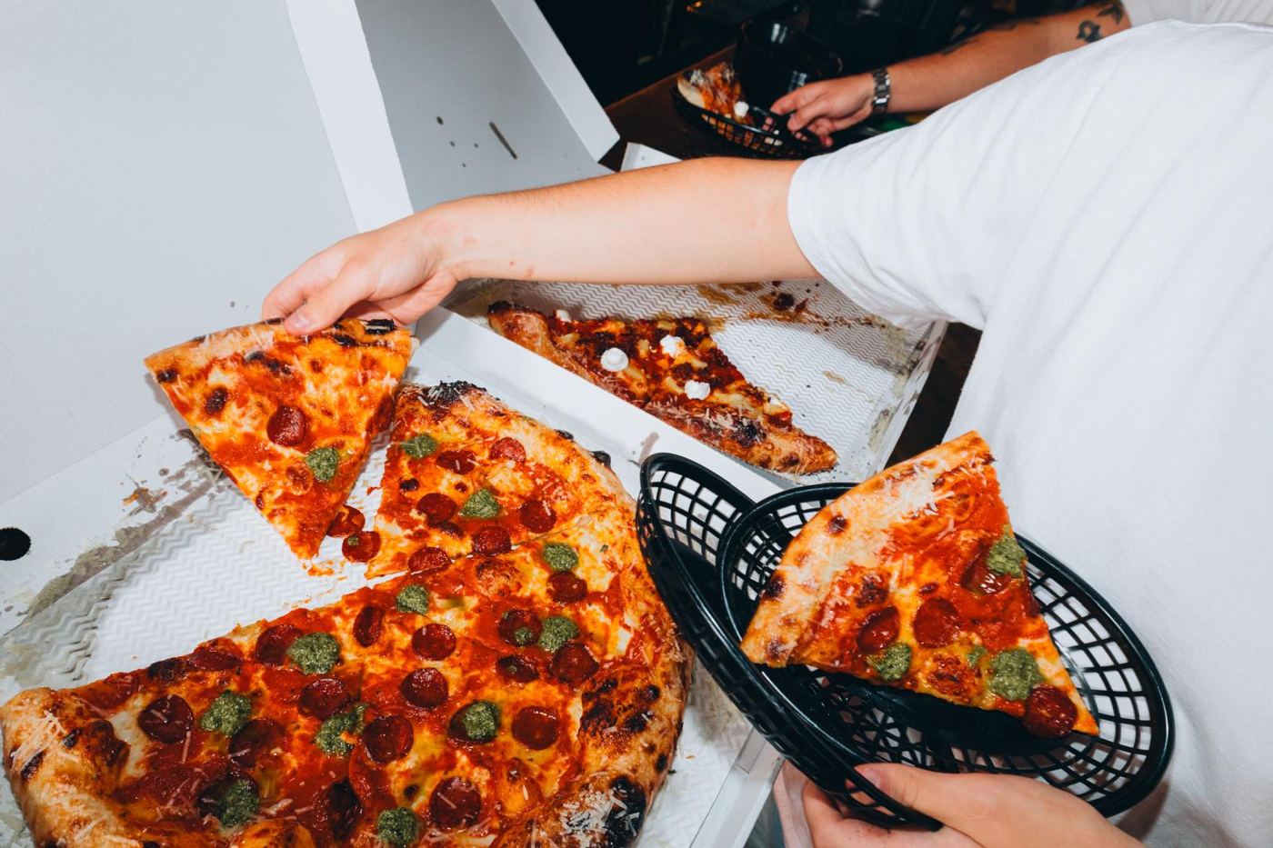 Hands grabbing pepperoni slices out of an open box