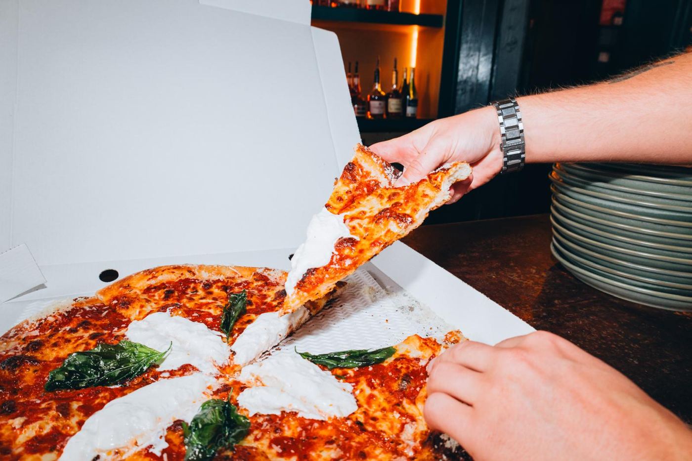 A slice pulled from a pizza topped with burrata and basil